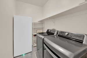 Laundry room featuring laundry area, light wood-style floors, and washing machine and clothes dryer