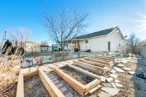 Rear view of house featuring a patio area, a vegetable garden, and fence