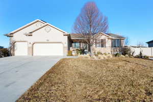 Single story home with stucco siding, concrete driveway, a front yard, fence, and a garage