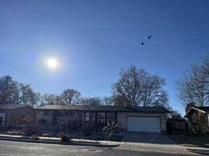 View of front of property with a garage, concrete driveway, brick siding, and a chimney