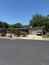Single story home featuring a garage, concrete driveway, and a chimney