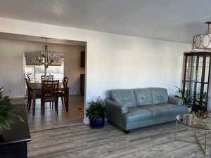 Living area with a textured ceiling, an inviting chandelier, and wood finished floors