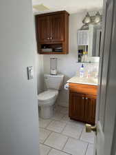 Half bathroom with a textured ceiling, toilet, visible vents, vanity, and tile patterned floors