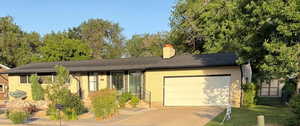 Ranch-style house with a garage, concrete driveway, brick siding, and a chimney