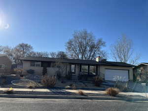 Ranch-style home with a garage, concrete driveway, brick siding, and a chimney