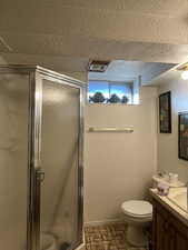 Bathroom with baseboards, toilet, a textured ceiling, vanity, and a shower stall