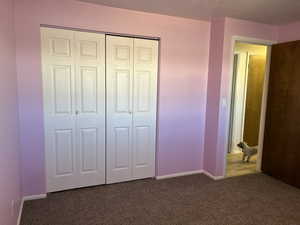 Unfurnished bedroom with carpet, a closet, and baseboards