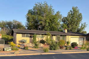 Ranch-style house featuring brick siding, an attached garage, and a chimney