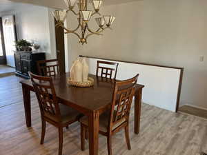 Dining area with light wood-type flooring and an inviting chandelier