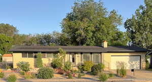 Ranch-style home featuring brick siding, an attached garage, a chimney, and driveway