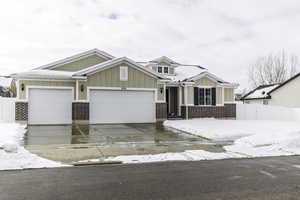 View of front facade with board and batten siding, concrete driveway, fence, and a garage