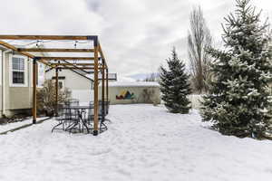 Yard layered in snow featuring fence and outdoor dining space