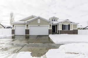 View of front of house with brick siding, concrete driveway, board and batten siding, fence, and a garage