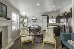 Interior space featuring baseboards, a fireplace with raised hearth, vaulted ceiling, a notable chandelier, and recessed lighting