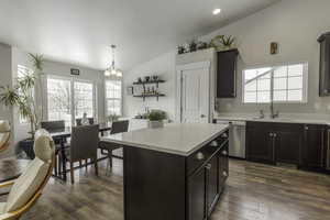 Kitchen with a center island, decorative light fixtures, light countertops, a sink, and dishwasher