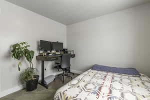 Bedroom with baseboards and dark colored carpet