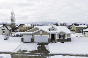 View of front facade featuring an attached garage, fence, a mountain view, board and batten siding, and brick siding