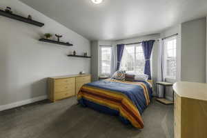 Carpeted bedroom featuring baseboards, vaulted ceiling, and a textured ceiling