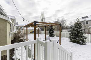 Yard layered in snow with a fenced backyard and a playground