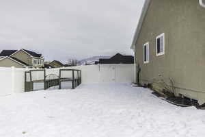 Snowy yard featuring a gate and fence