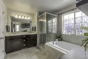 Full bathroom featuring a garden tub, double vanity, a sink, and a shower stall