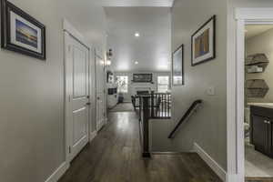 Hallway with dark wood-type flooring, recessed lighting, an upstairs landing, and baseboards