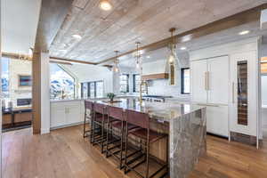 Kitchen featuring light wood finished floors, decorative backsplash, a spacious island, a breakfast bar area, and white cabinetry