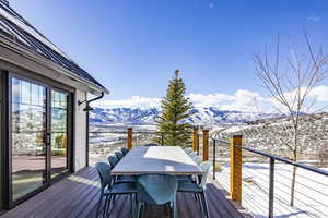 Snow covered deck featuring a mountain view and outdoor dining area