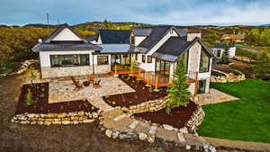 Rear view of house featuring metal roof, a yard, stone siding, a standing seam roof, and a patio area