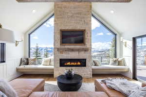 Living area with a wainscoted wall, a fireplace, lofted ceiling, a mountain view, and wood finished floors