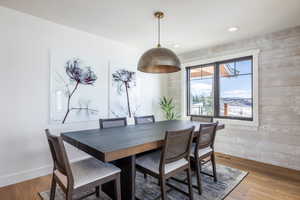 Dining room with light wood-style floors, recessed lighting, baseboards, and wood walls