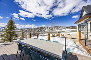 Snow covered deck with outdoor dining space and a mountain view