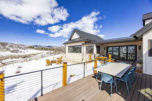 Snow covered deck with outdoor dining space and a mountain view