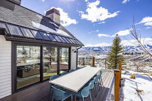 Snow covered deck featuring outdoor dining area and a mountain view