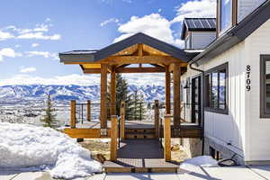 Snow covered deck featuring a mountain view and a gazebo