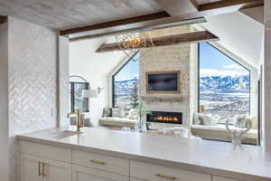 Kitchen featuring light stone counters, beam ceiling, white cabinetry, and a sink