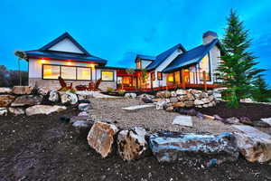 Rear view of house with stone siding, metal roof, a chimney, and a standing seam roof