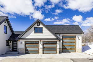 Modern farmhouse style home with a standing seam roof, metal roof, roof with shingles, and stone siding