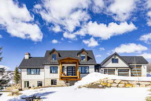 Modern inspired farmhouse featuring a garage, a chimney, metal roof, a standing seam roof, and board and batten siding