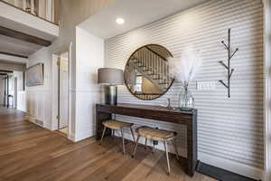 Hallway featuring visible vents, a decorative wall, wood finished floors, and wainscoting