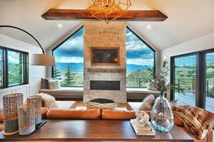 Living room featuring lofted ceiling with beams, a fireplace, and plenty of natural light