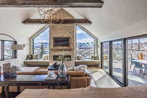 Living room with a large fireplace, hardwood / wood-style floors, beamed ceiling, and an inviting chandelier