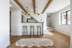 Kitchen featuring backsplash, wood finished floors, beam ceiling, and a decorative wall