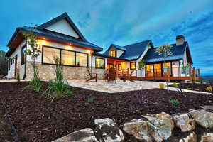 Back of house with stone siding, a standing seam roof, a patio, and metal roof