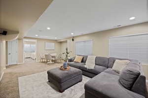 Carpeted living area with visible vents, baseboards, and recessed lighting