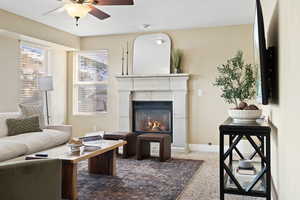 Living area with a textured ceiling, a glass covered fireplace, a ceiling fan, and baseboards