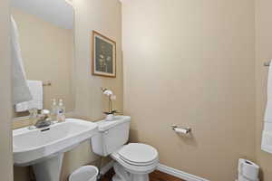 Half bathroom featuring a sink, wood finished floors, toilet, and baseboards