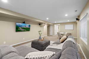 Carpeted living room with recessed lighting, visible vents, and baseboards