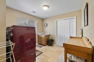 Bathroom featuring a textured ceiling, a sink, visible vents, and baseboards