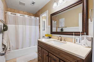 Full bathroom with visible vents, a textured ceiling, vanity, and shower / bath combo with shower curtain